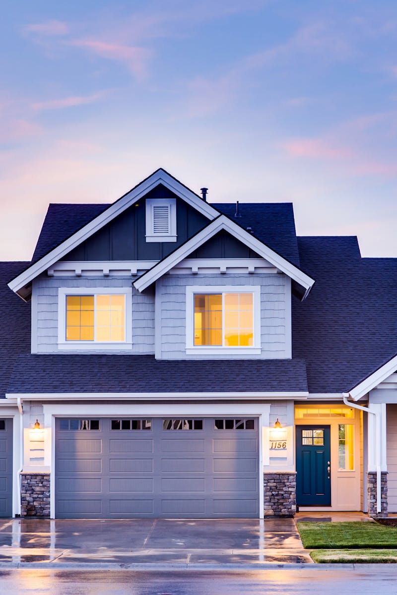 Beautiful two-story house with illuminated windows and garage at dusk.